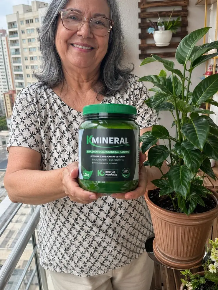 Regina na varanda do apartamento com sua planta